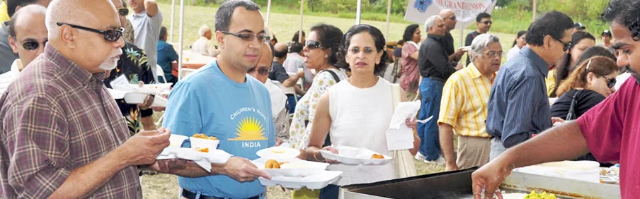 Alumni sharing food at an outdoor TNMC picnic